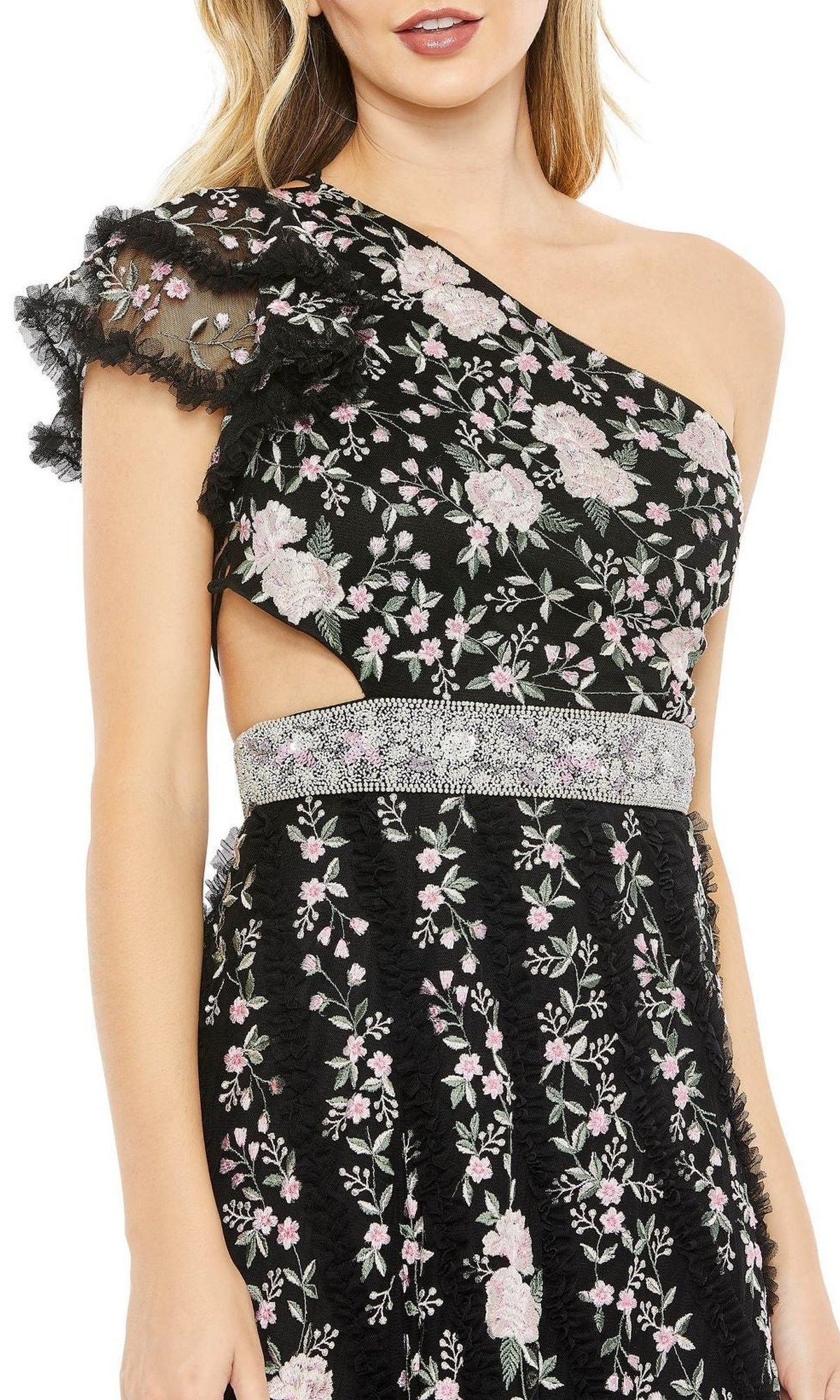 A woman wearing the Long Formal Dress 70160 by Mac Duggal—a black one-shoulder evening gown with pink floral embroidery, lace details, a silver waistband, and a waist cutout—perfect for formal occasions.